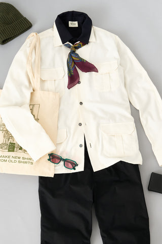 White shirt with navy polo, patterned scarf, and black pants on a light grey background