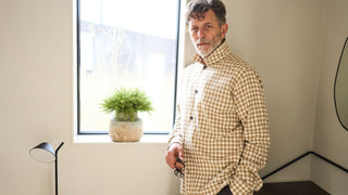 A man wearing a beige and brown gingham overshirt.