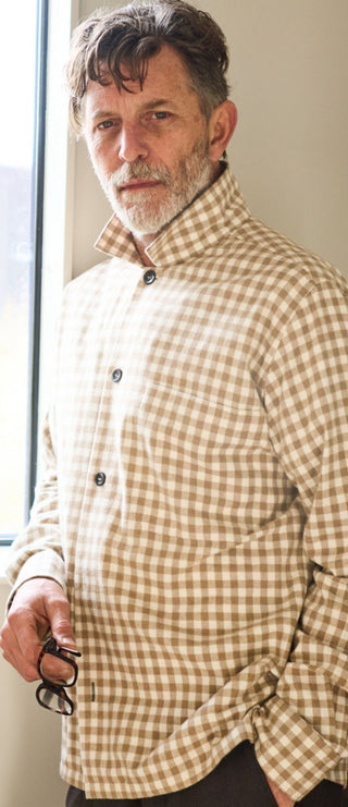 A man wearing a beige and brown gingham overshirt.
